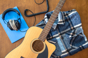 Music background with guitar, headphones and notepad, top view.