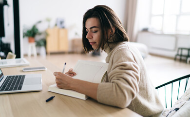 Woman writing in diary and working at home
