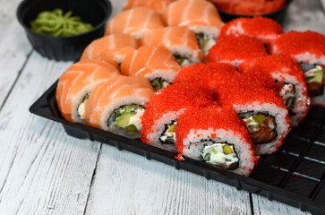 Fresh sushi on a wooden table. Roll Philadelphia sushi with salmon, smoked eel, cucumber, avocado, cream cheese, red caviar. Sushi menu. Japanese food.