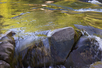 Rough current of a mountain river and stones. Beautiful movement of water in the wild. Freshness of nature. Wildlife photography for background