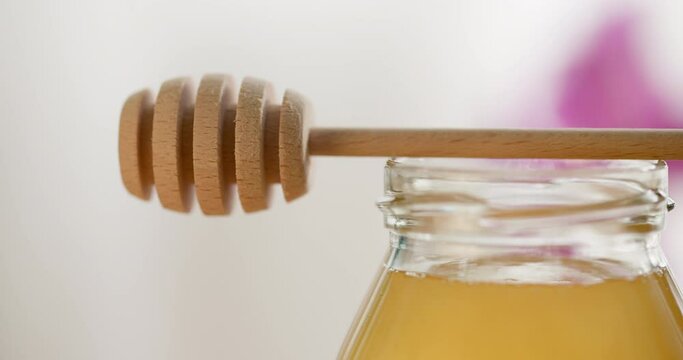 Honey background. Sweet honey in a glass jar and a honey spoon on a wooden table.
