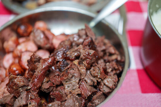 pedaços de carne bovina e linguiça de porco assados e servidos dentro de uma bandeja sobre a mesa