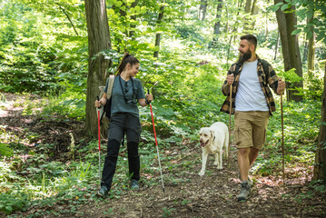 Young happy couple and their dog at hiking through the woods enjoying the sight. Two nature lovers...