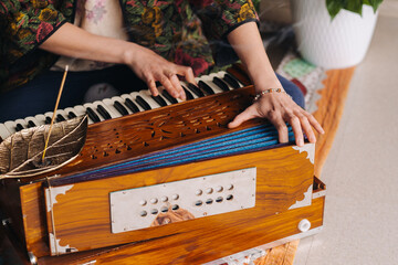 Hands of a woman sitting on the floor and playing the harmonium during the practice of kundalini...