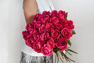 Woman with  bouquet of red roses. Beautiful fresh bright flowers for  holiday. Woman with beautiful flowers in her hands indoors background.  bouquet of roses for  flower shop.