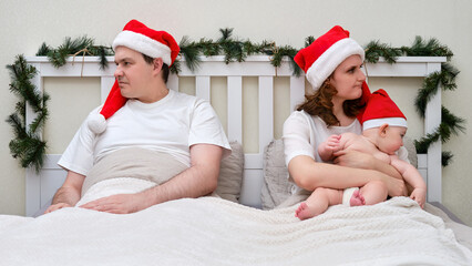 Obraz premium Quarrel of husband and wife with baby on bed decorated for christmas and new year, family couple in home bedroom