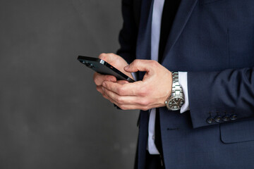 young businessman in a dark blue suit working in the office, typing on a mobile phone