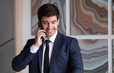 young businessman in a dark blue suit working in the office, talking by mobile phone