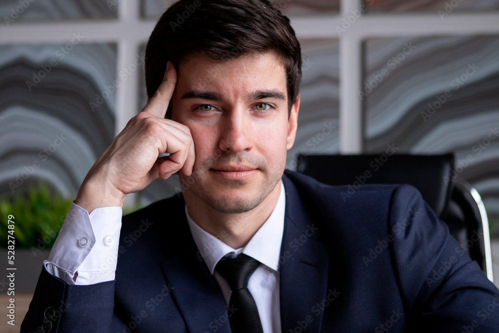 Wall mural portrait of young businessman in a dark blue suit working in the office