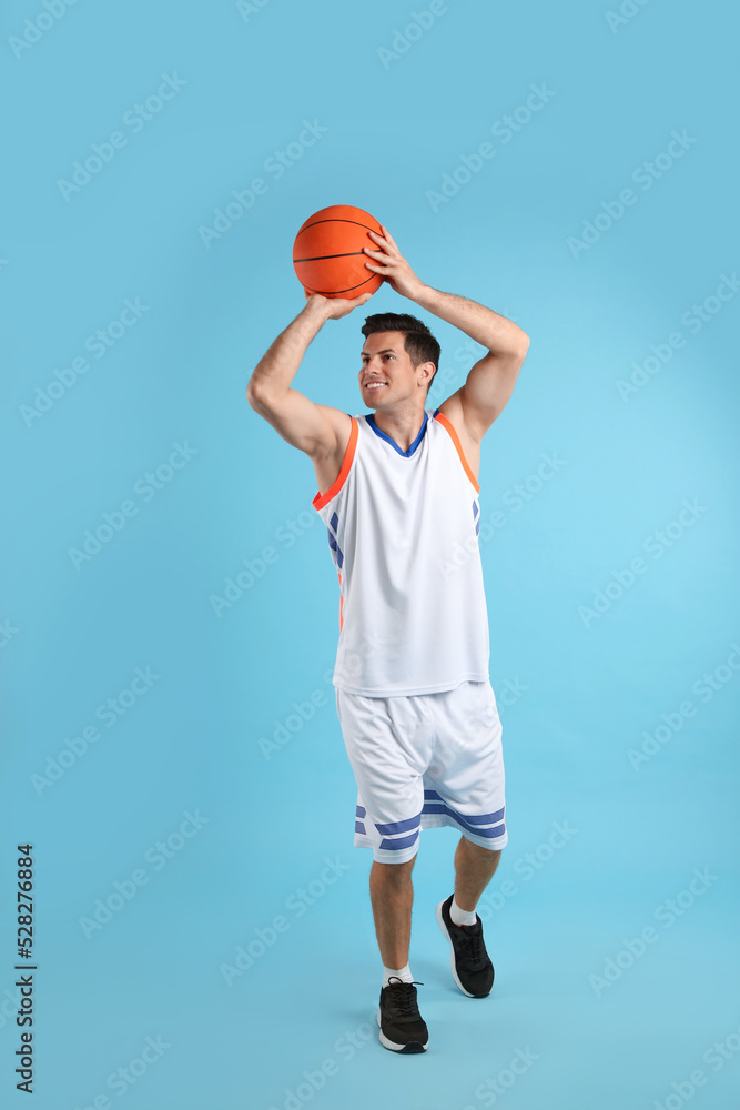 Poster Professional sportsman playing basketball on light blue background