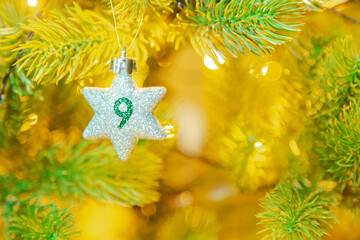 Weihnachtsschmuck (Stern) am Baum mit einer Zahl (9) vom Weihnachtskalender