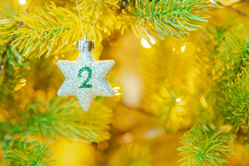 Weihnachtsschmuck (Stern) am Baum mit einer Zahl (2) vom Weihnachtskalender