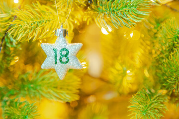 Weihnachtsschmuck (Stern) am Baum mit einer Zahl (18) vom Weihnachtskalender