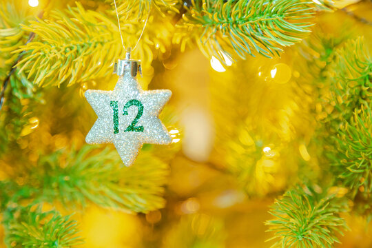 Weihnachtsschmuck (Stern) am Baum mit einer Zahl (12) vom Weihnachtskalender