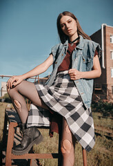 Outdoor portrait of beautiful grunge (rock) girl standing on stairs. Informal model dressed in jean...