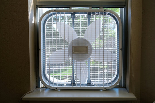 Classic Window Box Fan Inserted In Home Room Window Indoor Cooling Air Conditioning Vetilation Equipment. Front View Hight Quality Close Up Photo.