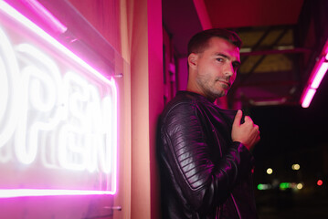 Fototapeta na wymiar Serious man stands next to a neon sign 