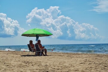 an elderly couple under an umbrella on the beach