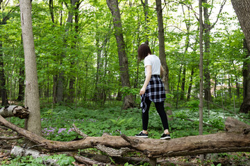 Naklejka na ściany i meble Woman balancing on log in woods