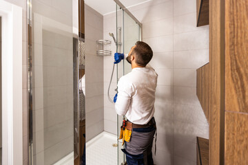 Plumber installing a shower cabin in bathroom - obrazy, fototapety, plakaty