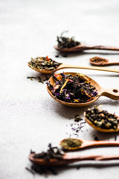 Overhead view of wooden spoons with assorted teas lined up on a table