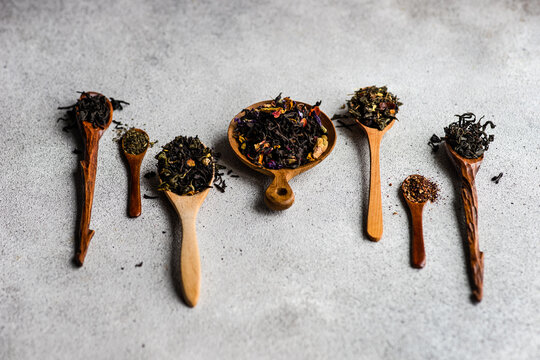 Overhead view of wooden spoons with assorted teas lined up on a table