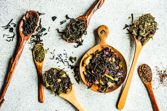 Overhead view of wooden spoons with assorted teas lined up on a table