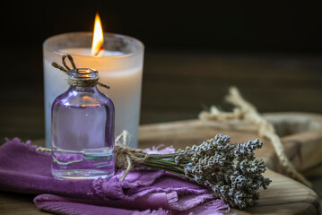 Obraz na płótnie Canvas Glass bottle Lavender essential oil dried seed aromatherapy spa massage concept. herb Purple candle wood table background sea salt still life rustic cutting board napkin