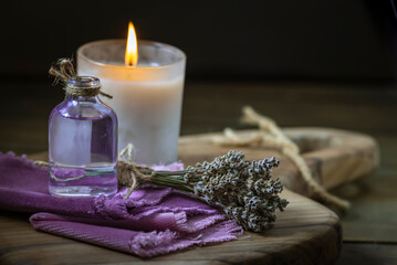 Obraz na płótnie Canvas Glass bottle Lavender essential oil dried seed aromatherapy spa massage concept. herb Purple candle wood table background sea salt still life rustic cutting board napkin
