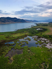 Aerial View of Okanagan Lake with farm lands and mountain landscape. Cloudy Sunset Sky. Near...