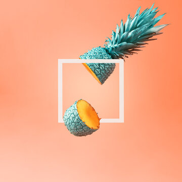 Creative summer layout of a frame and a cut pineapple on an orange background.