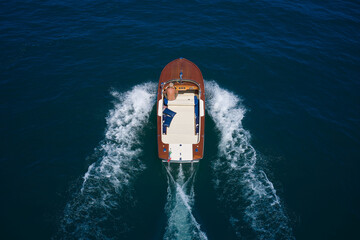 Wooden expensive boat fast movement on dark water top view. Big expensive wooden open boat with a...