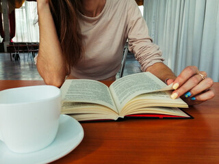 read a book in a cafe at a table with a cup of coffee.
