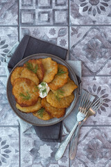 Classic potato pancakes with sour cream sauce served on a gray ceramic dish. Traditional belarusian potato pancakes draniki. Top view.