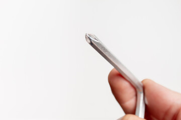 Human hand holding a Phillips screwdriver on white background with copy space