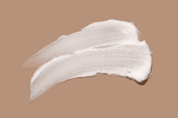 White cosmetic cream lotion swatch smear smudge on brown color background.