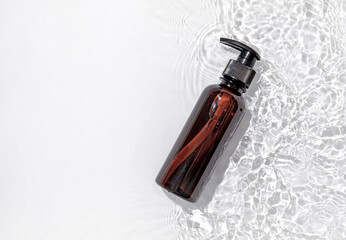 Amber cosmetic bottle on the water surface. Blank label for branding mock-up. Summer water pool...