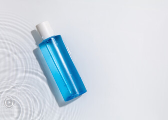 Blue cosmetic bottle on the water surface. Blank label for branding mock-up. Summer water pool...