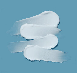 White cosmetic cream lotion swatch smear smudge on blue color background.