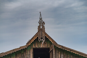 Top ridge, siding and gable beautiful carved platbands on the roof of a wooden house rustic old sky.