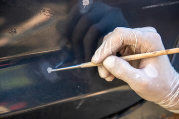 The car painter pointwise brings the primer with a brush into the paint layer.