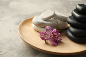Fototapeta na wymiar Spa stones and orchid flower on grey table, closeup