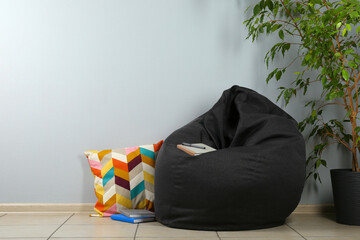 Black bean bag chair near light grey wall in room. Space for text - obrazy, fototapety, plakaty