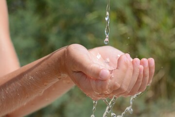Naklejka na ściany i meble Pouring water into kid`s hands outdoors, closeup