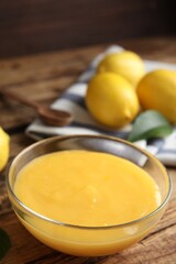 Delicious lemon curd in glass bowl on wooden table
