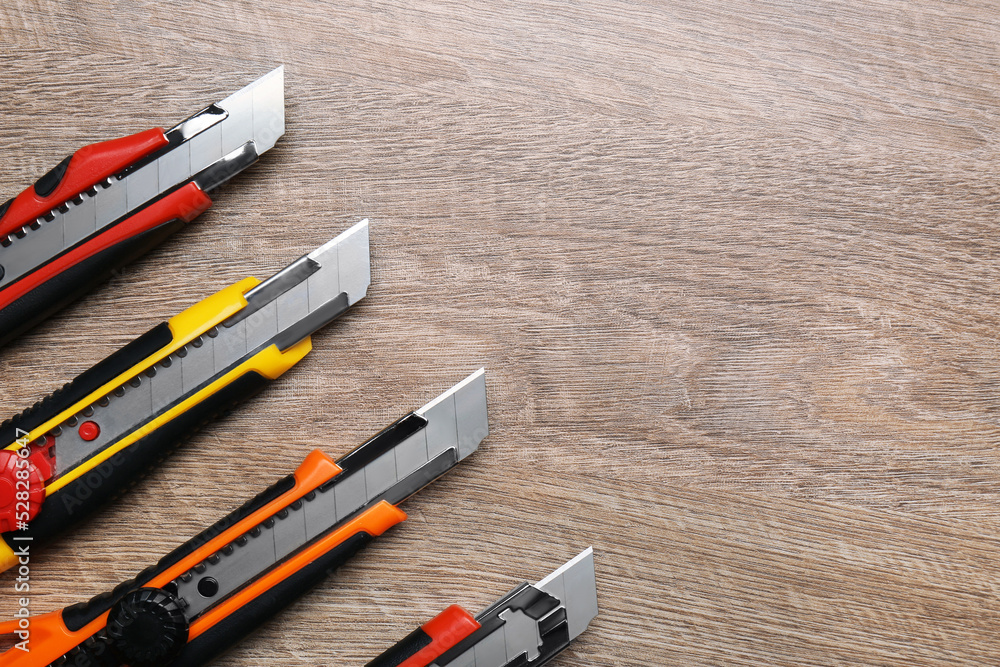 Canvas Prints Many different utility knives on wooden table, flat lay. Space for text