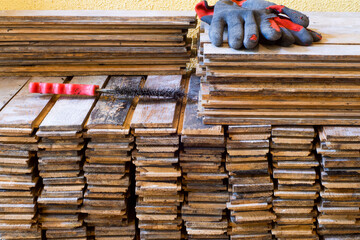 Piles of old wooden boards after initial cleaning with used tools and destroyed gloves. Renovation of the ancient wooden floor. Old parquet floor of a tenement house. Hard industrial work concept.