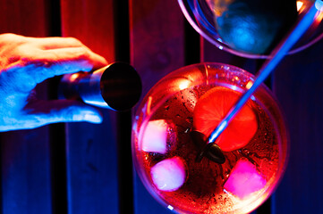 Bartender serving liqueur in a red glass with colored lights
