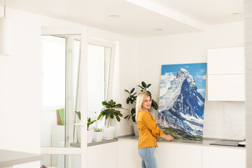 Woman hanging a photo canvas on a wall.