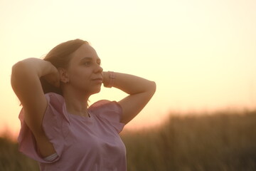 Fototapeta na wymiar Young beautiful woman looking away, touching short hair against sky on sunset.